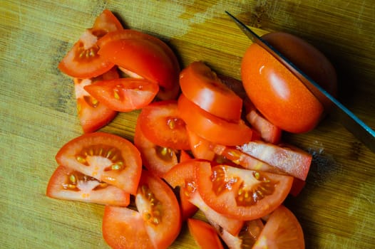 Sliced tomatoes and knife. cooking process. pieces of juicy tomato on a wooden board