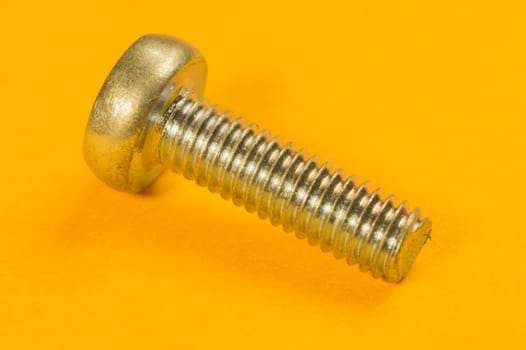Steel screw on a yellow background. working tools