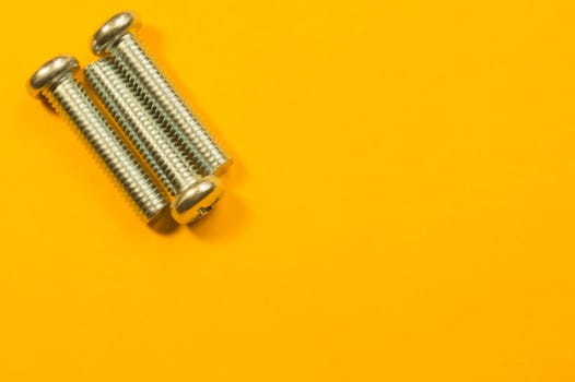 Steel screw on a yellow background. working tools