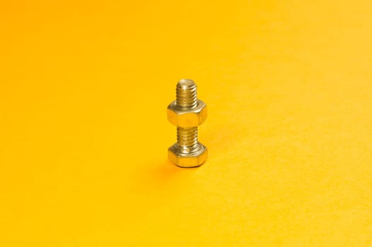 Steel screw on a yellow background. working tools