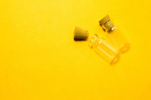 Empty little bottles with cork stopper isolated on yellow. glass vessels. transparent containers. test tubes. copy space