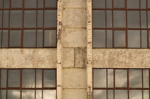 Big windows of the factory on the cement wall background