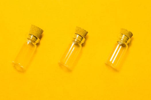 Empty little bottles with cork stopper isolated on yellow. glass vessels. transparent containers. test tubes