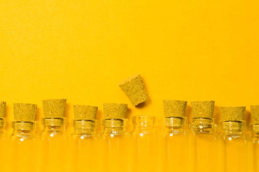 Empty little bottles with cork stopper isolated on yellow. glass vessels. transparent containers. test tubes