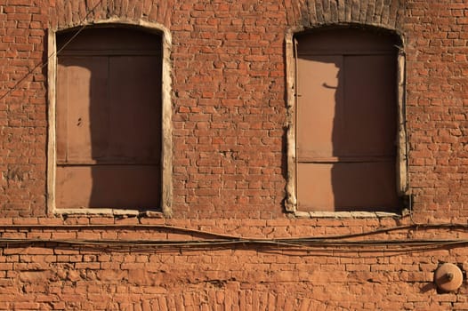 Old brown brick wall with boarded windows background