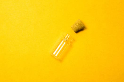 Empty little bottle with cork stopper isolated on yellow. glass vessel. transparent container. test tube