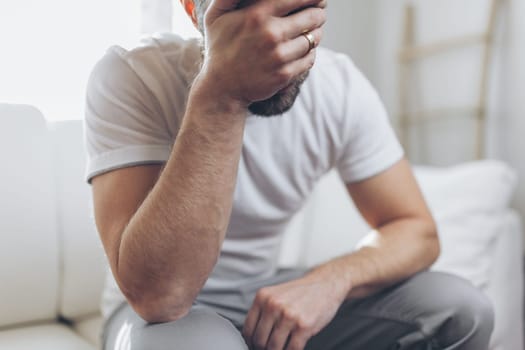 Heartbroken man at home holding a wedding ring