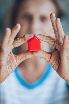 Elderly woman holding a small house in her hands