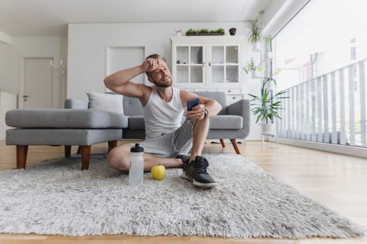 Handsome young man working out at home in the living room