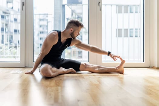 Young handsome man practicing yoga at home
