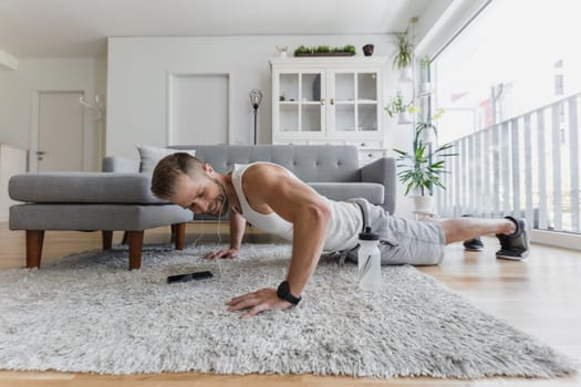 Handsome young man working out at home in the living room