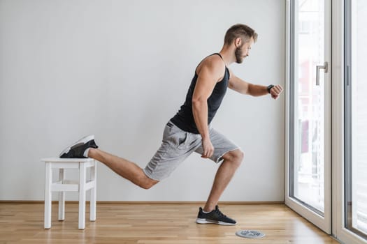Handsome young man working out at home with a smart watch