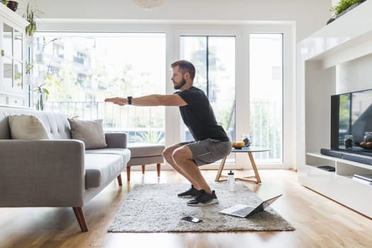 Handsome young man working out at home in the living room