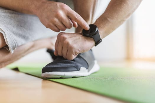 Handsome young man working out at home with a smart watch