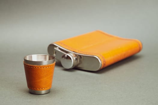 Stainless flask with leather covering. metallic shot glass. travel personal accessory set for alcohol drinks. copy space