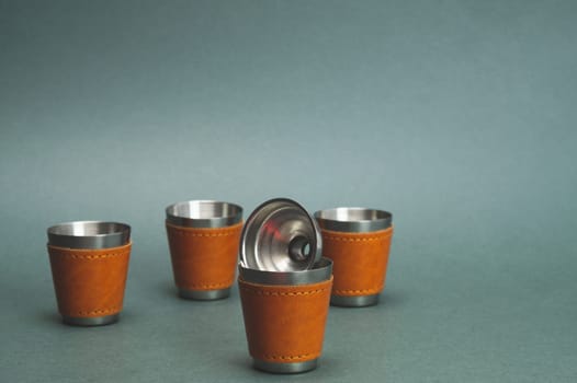 Metallic shot glasses and funnel. travel shot glass for alcohol with leather casing over the stainless steel. personal accessory set. copy space