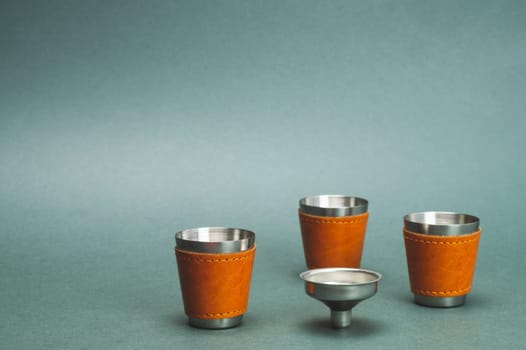 Metallic shot glasses and funnel. travel shot glass for alcohol with leather casing over the stainless steel. personal accessory set. copy space
