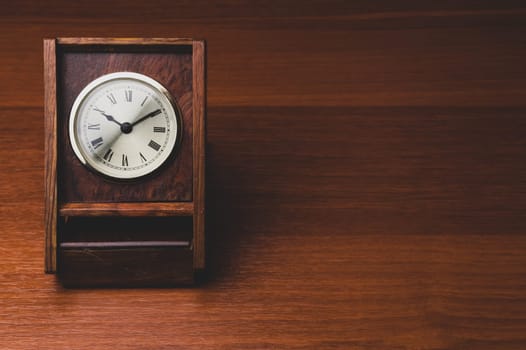 Retro wooden clock. square shaped vintage clock with round dial. wood table. copy space