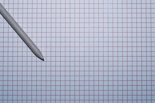 Pen lies on checkered paper. squared grid surface
