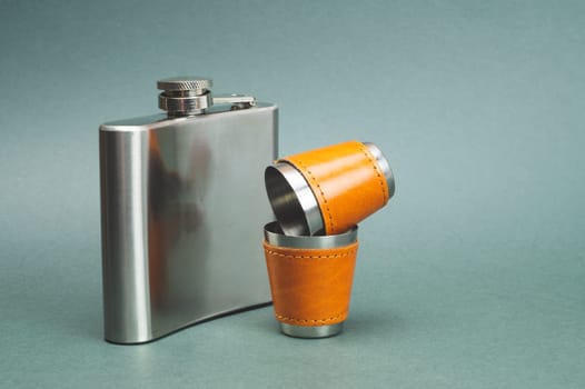 Stainless steel flask with pair of shot glasses. travel shot glass for alcohol with leather casing over the metal. personal accessory set