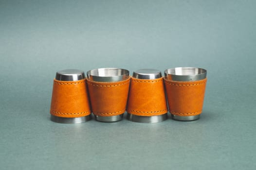 Metallic shot glasses in a row. travel shot glass for alcohol with leather casing over the stainless steel. personal accessory set. copy space