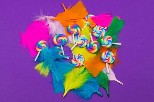 Lollipops on the feathers. spiral candies on a purple background. festive decoration