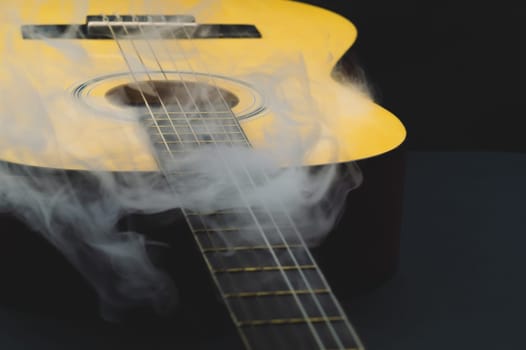 Guitar in smoke close up. acoustic musical instrument. strings on the guitar neck
