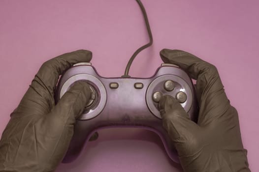 Hands in protective gloves holding the gamepad. playing video games