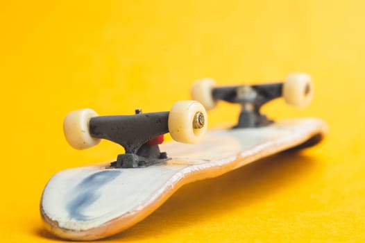 Small skateboard on yellow background. tiny skate for fingers. fingerboard close up. home leisure concept. copy space