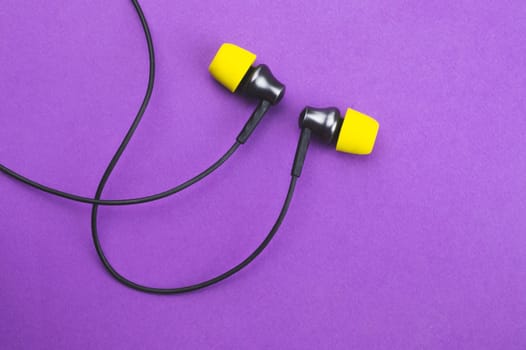 Earphones with yellow ear cushions on a purple background. in-ear headphones. audio equipment