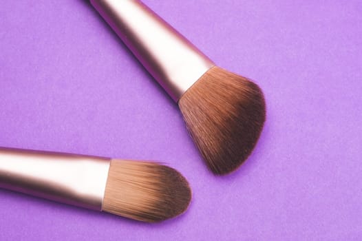 Makeup brushes on purple background. various cosmetic brushes close up. skin care accessories
