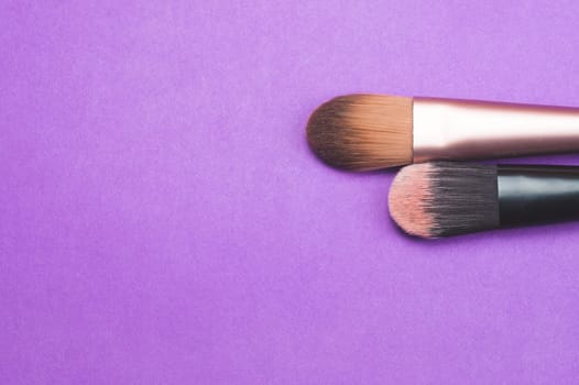 Makeup brushes on purple background. various cosmetic brushes close up. skin care accessories