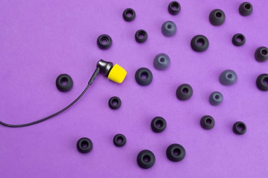 Individuality concept. earphone with yellow ear cushion between of gray embouchures. in-ear headphones. modern style. audio equipment