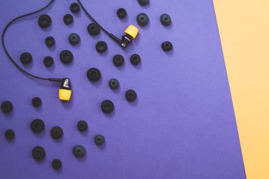 Individuality concept. earphones with yellow ear cushions between of gray embouchures. in-ear headphones. modern style. audio equipment