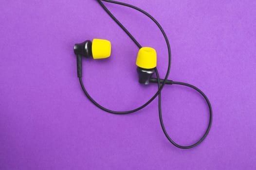 Earphones with yellow ear cushions on a purple background. in-ear headphones. audio equipment
