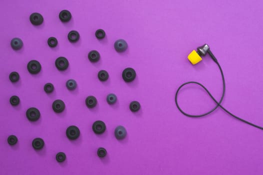 Individuality concept. earphone with yellow ear cushion opposite of gray embouchures. in-ear headphones. audio equipment