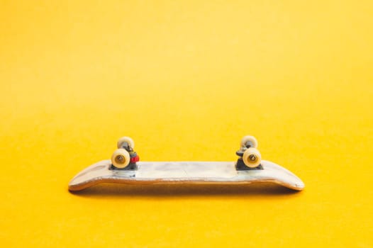 Small skateboard on yellow background. tiny skate for fingers. fingerboard close up. copy space