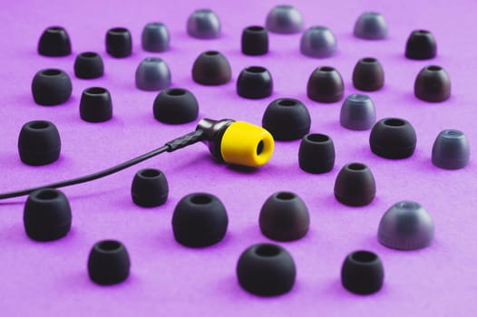 Individuality concept. earphone with yellow ear cushion between of gray embouchures. in-ear headphones. modern style. audio equipment