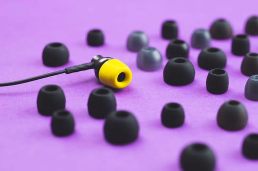 Individuality concept. earphone with yellow ear cushion between of gray embouchures. in-ear headphones. modern style. audio equipment