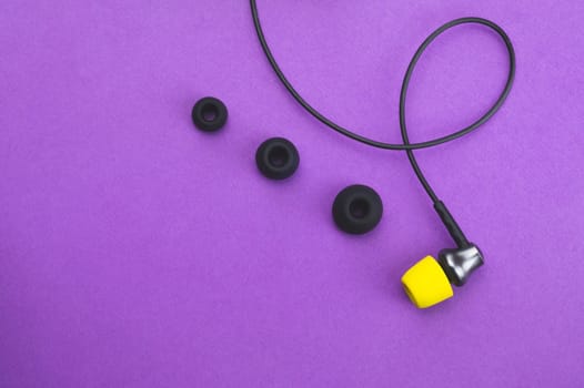 Individuality concept. earphone with yellow ear pad in the end of row of gray embouchures. in-ear headphones. audio equipment. copy space