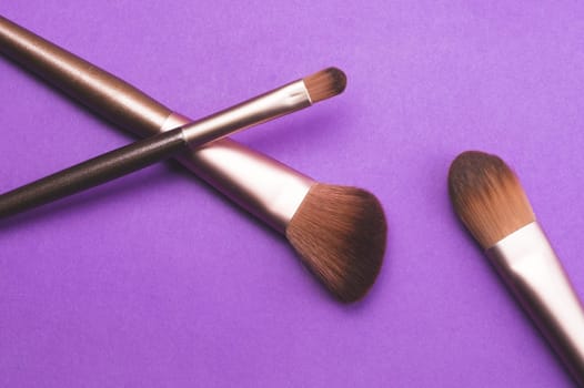 Makeup brushes on purple background. various cosmetic brushes close up. skin care accessories