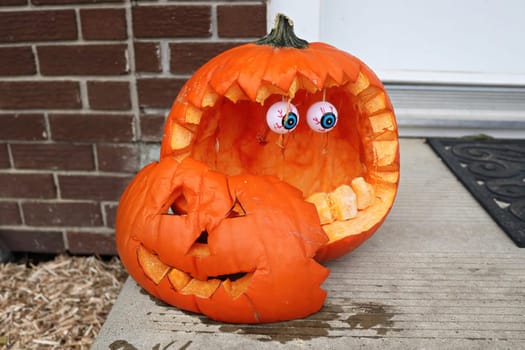 A carved pumkins sitting on a doorstep.