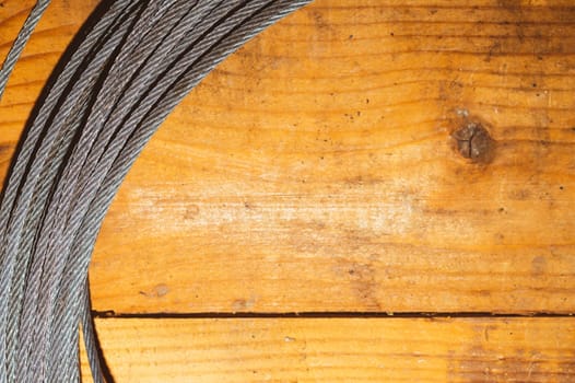 Steel cable on wooden background. hank of metal rope lies on the table. work tool
