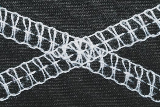 White seams on black fabric. stitches on textile material close up