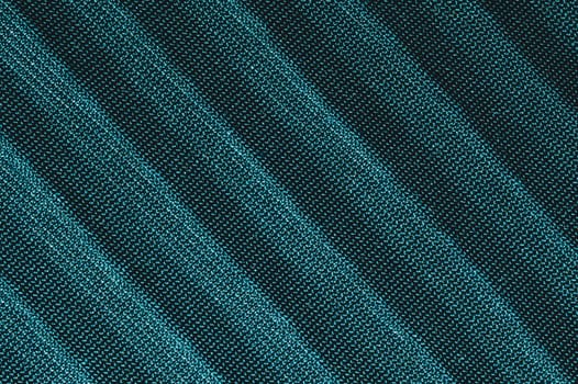 Green textile with parallel folds. fabric texture with flat creases. cloth background close up