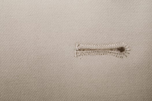 Beige fabric with a button hole. vintage jacket detail. textile close up background