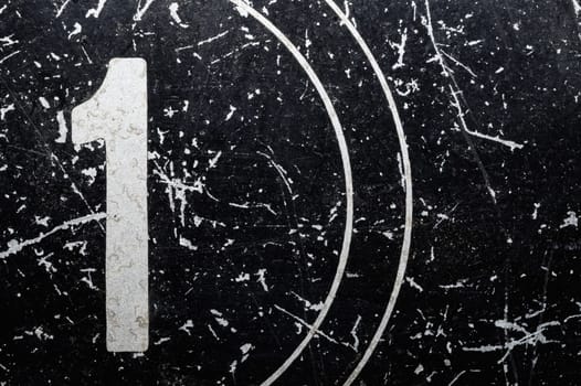 Number one painted on a metal surface. black iron plate with digit 1. scratched paint on steel. rough texture. industrial background
