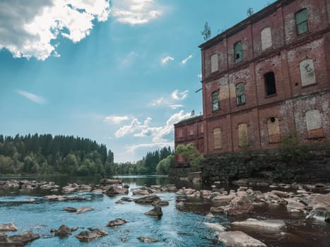 Abandoned factory on the water edge. old building on the rocky river. brown brick wall. water stream