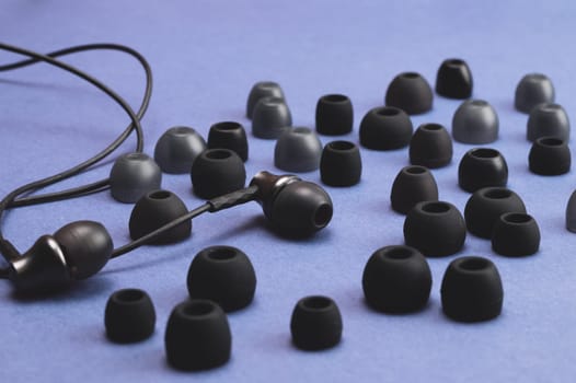 Earphones between of ear cushions on blue background. in-ear headphones and lot of embouchures. audio equipment