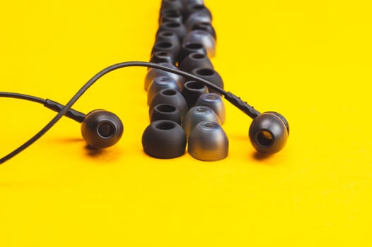 Earphones between of ear cushions on yellow background. in-ear headphones with many embouchures. modern style. audio equipment
